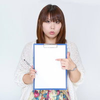 白い紙のメモを正面に向けて見せる女性の写真