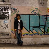 グラフィティの壁の前に立つジャケットの若者の写真