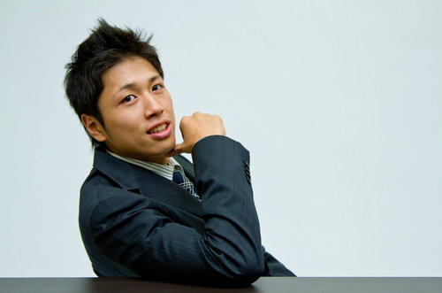 水色の壁の前で「それでどう？」と手を差し出して確認するビジネスマン