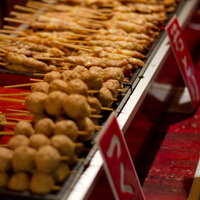 赤い看板の屋台に並ぶ焼き色のついた丸いつくねの串の写真