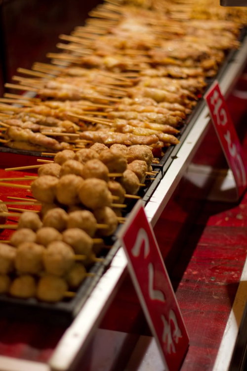 赤い看板の屋台に並ぶ焼き色のついた丸いつくねの串