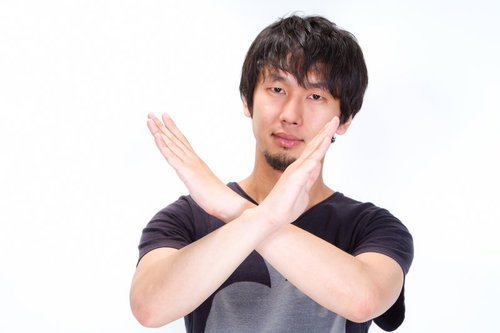 両腕でバツマークを作って拒否する男性のポーズ