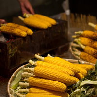 炭火で焼き色がつく出店のやきもろこしの串の写真