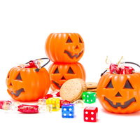 オレンジのかぼちゃランタンと色とりどりのハロウィン用お菓子の写真
