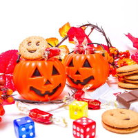 色とりどりのお菓子に囲まれたおばけ顔のハロウィンかぼちゃの写真