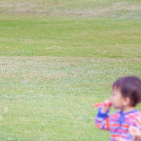 青空の下でストローからシャボン玉を吹く子供の写真