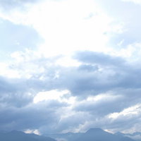 白い雲の間からそびえるアルプスの雪山と山々の写真