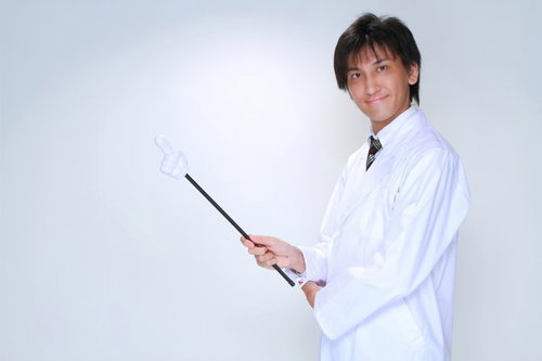 指示棒を持って前方を指す白衣の男性の案内ポーズ