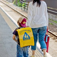駅のホームを歩く親子の後ろ姿の写真