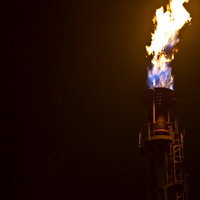 暗い空を背景に煙突の先から燃え上がる炎の写真