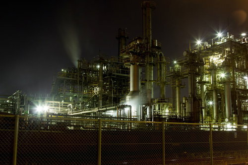 フェンス越しにライトアップされる工場夜景