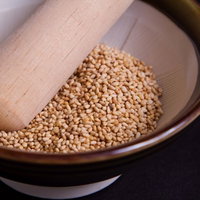 すり鉢に入ったゴマと木のしゃもじの写真