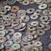 布の上に散らばった穴あきの古銭の写真