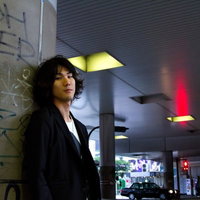 井の頭線下の歩道とこちらを向く男性の写真