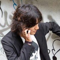 落書きの壁に手をかけ電話する男性の写真