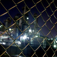 金網フェンス越しの工場の夜景の写真