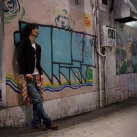 渋谷の薄暗い高架下の落書きによりかかる若者の写真