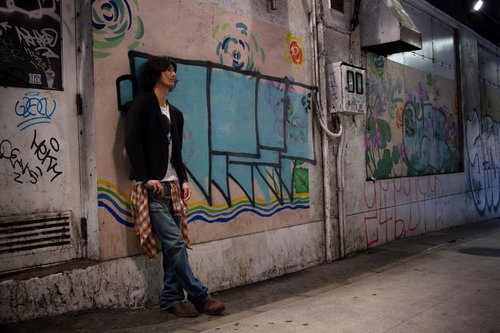 渋谷の薄暗い高架下の落書きによりかかる若者