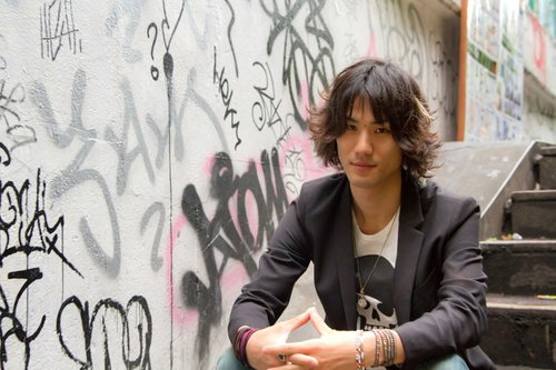 落書きだらけのかべの前でこちらを見る男性