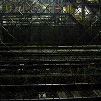 線路越しに見る夜の工場プラントの写真