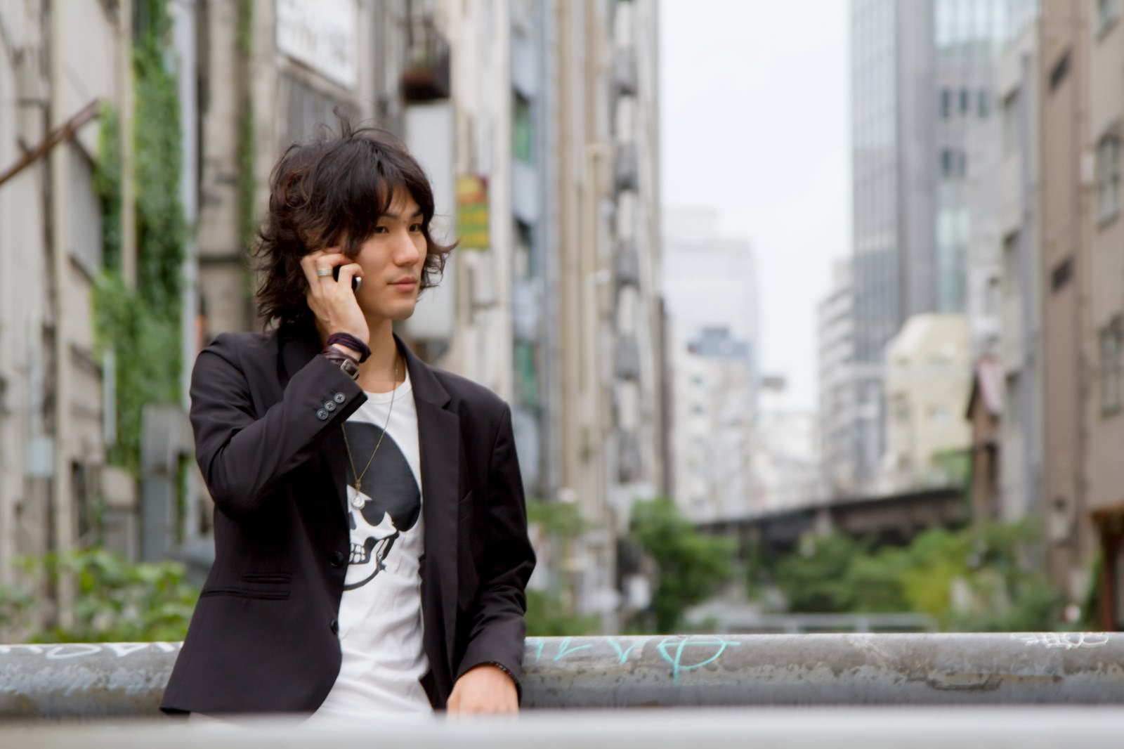 渋谷川の橋の上で電話する男性［モデル：村田裕章］