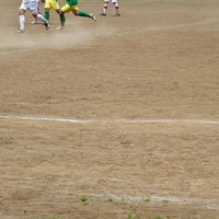 グラウンドで試合中のサッカー選手たちの写真