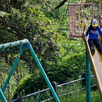 滑り台をすべる子供のいる公園の遊具の写真