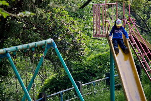 滑り台をすべる子供のいる公園の遊具
