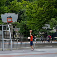 代々木公園のバスケットコートでシュート練習する少年の写真