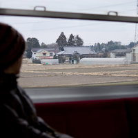 窓際の席で景色を眺めながら田舎に帰省する電車の乗客の写真