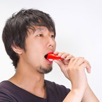 パーティー用クラッカーを口にくわえてパフォーマンスする男性の写真