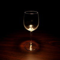 暗闇の中で光を受けて光る透明なグラスの写真