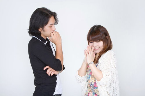 両手を合わせて彼氏にお願いのポーズをする笑顔の女性