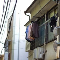 洗濯物が干されたベランダと外階段のある下町のアパートの写真