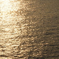 オレンジの夕焼け空が水面に映り込む反射する水辺の風景の写真