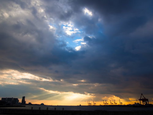 厚い雲の隙間から漏れるオレンジの夕焼けの光
