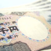 白い台に重ねた２千円札と一万円札の写真