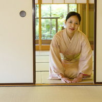 障子の奥でお辞儀をする着物の女将の写真