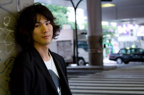 窓のある部屋で壁に寄り掛かる若者