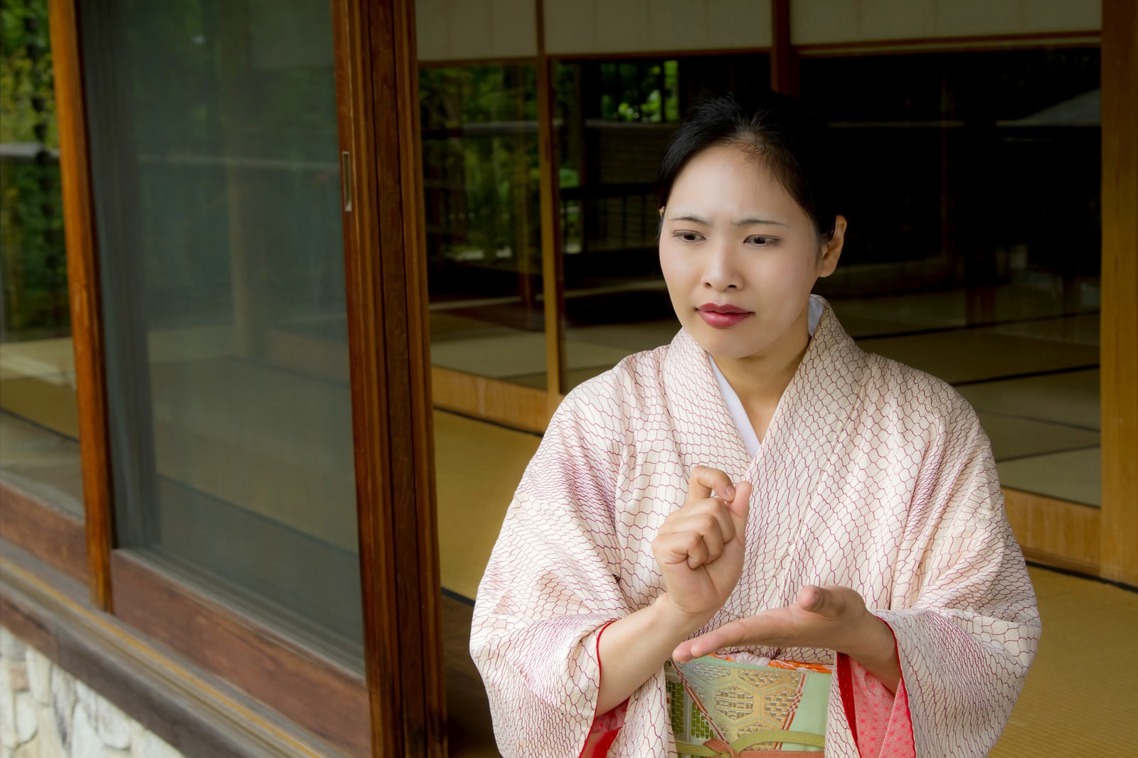 縁側で手を組んで悩む着物の女将さん［モデル：きせんひろみ］