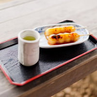 串に刺さったタレ付きのお団子と山小屋の休憩所の写真