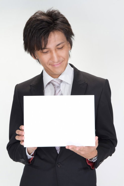 白いボードを手に持って内容を確認するスーツ姿のビジネスマン