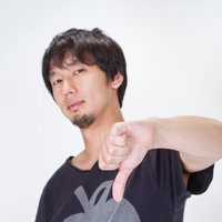 両手の親指を下に向けてブーイングのポーズをする男性の写真