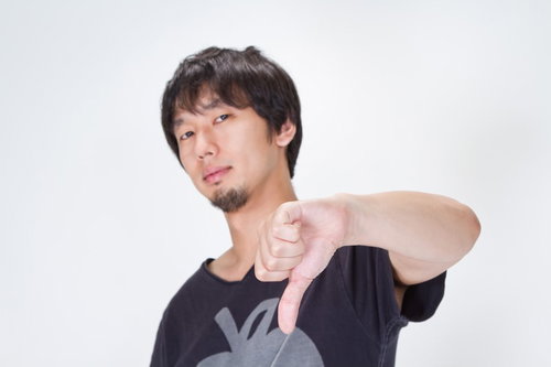 両手の親指を下に向けてブーイングのポーズをする男性