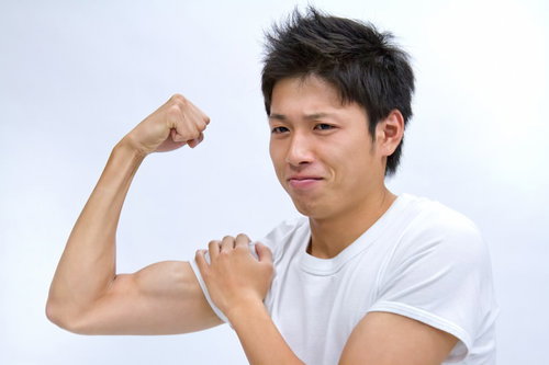 白い背景の前で腕を曲げて力こぶを見せる笑顔の男性