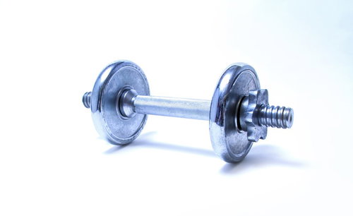 黒い床に置かれた銀色のダンベルのクローズアップ