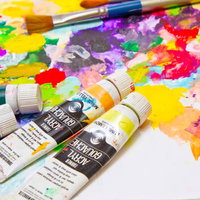 木のパレットの上にチューブから出した絵の具が散らばるアート風景の写真
