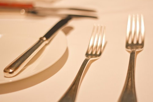 白い皿の上に並んだ銀色のフォークとナイフのテーブルセット