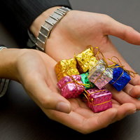 「ほら、ご褒美だよ」とプレゼントの箱を差し出すスーツ姿の手元の写真