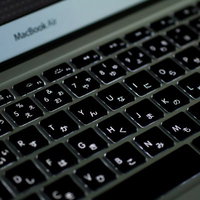 暗い部屋でバックライトが光るMacBook Airのキーボードの写真